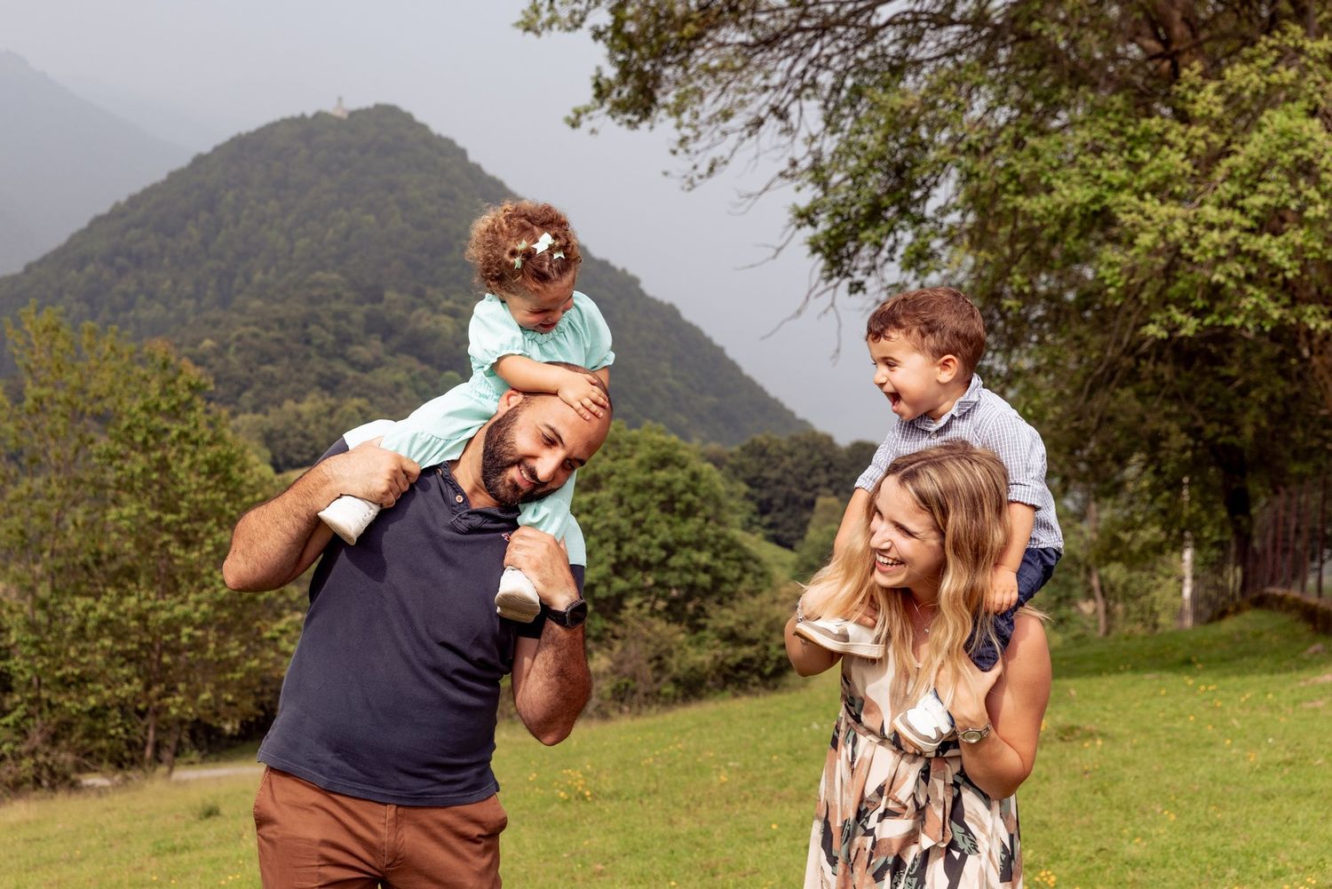 Family enjoying playful moments together in mountain field.