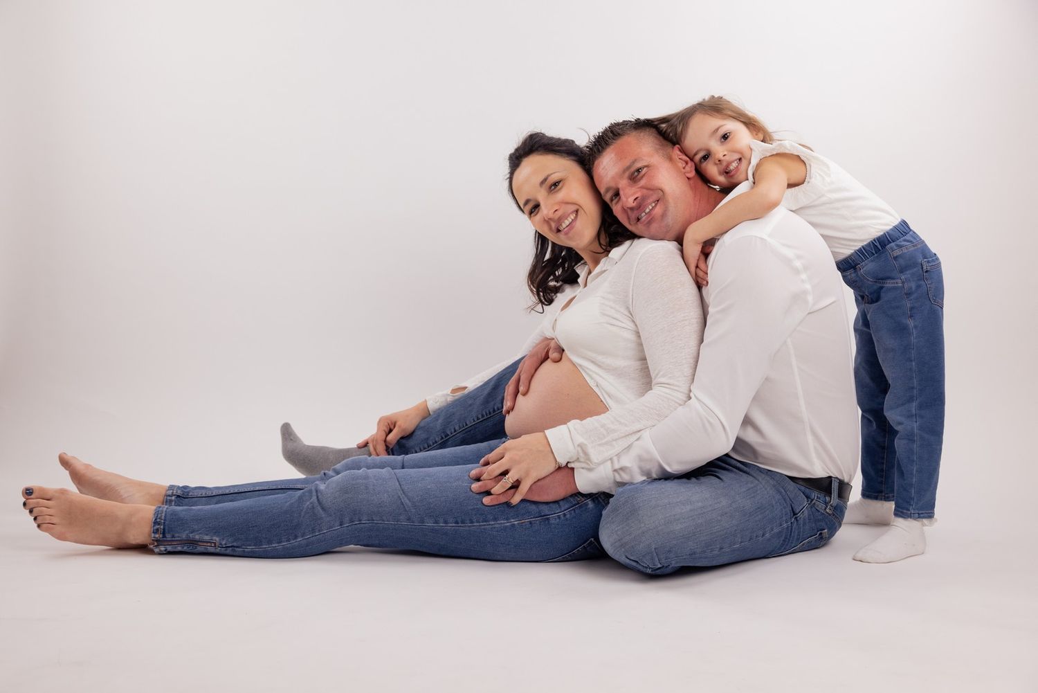 Family sitting together on floor during casual maternity photoshoot.
