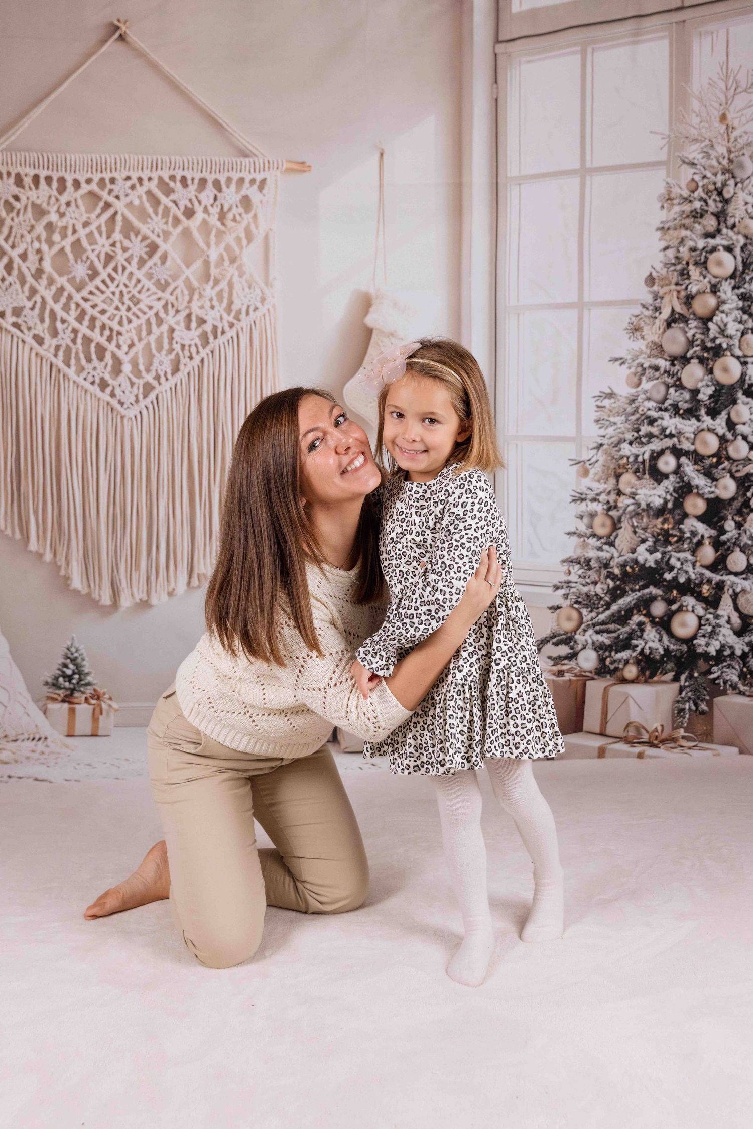 Bright holiday photo setup with a decorated Christmas tree and macrame wall hanging.