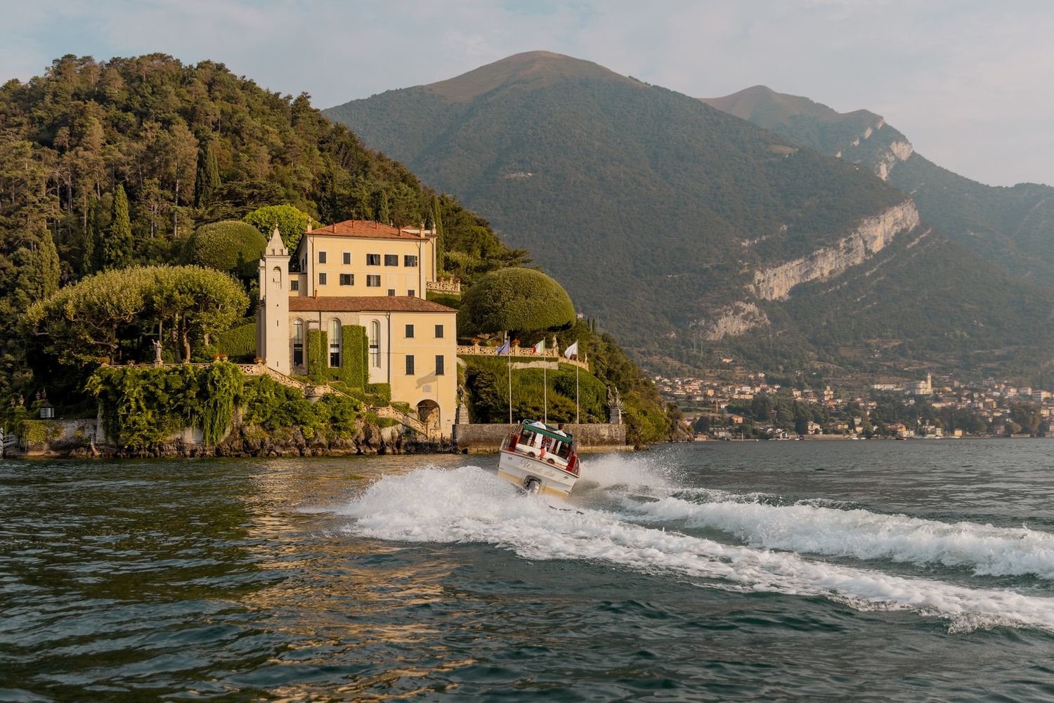 Vintage wooden speedboats cruise past an elegant lakeside villa in Italy.