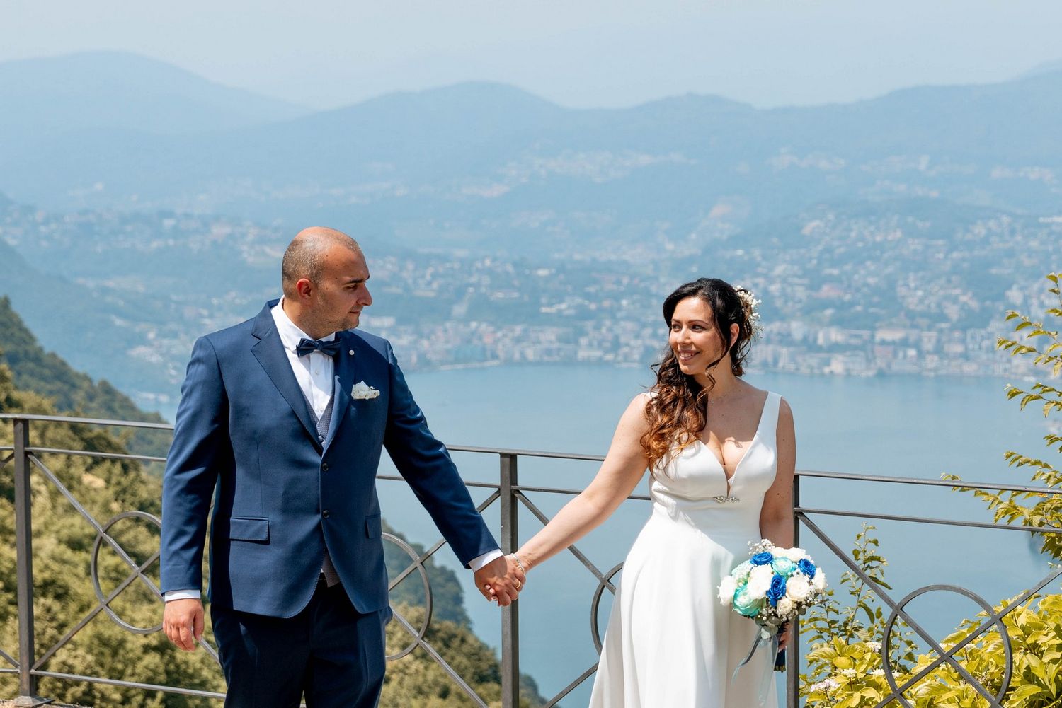 A couple shares romantic moments on a scenic mountain overlook with lake views.