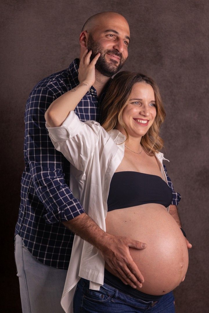 Casual maternity portrait against textured brown background showing couple's connection.