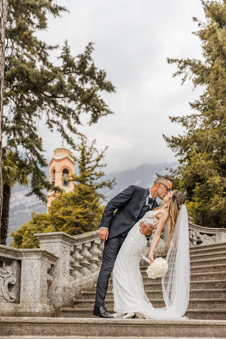 Elegant wedding photos on grand stone steps surrounded by evergreen trees.