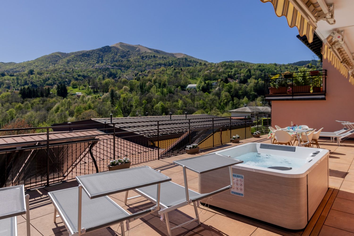 Panoramic mountain view from a terrace with sunbeds and outdoor furniture.