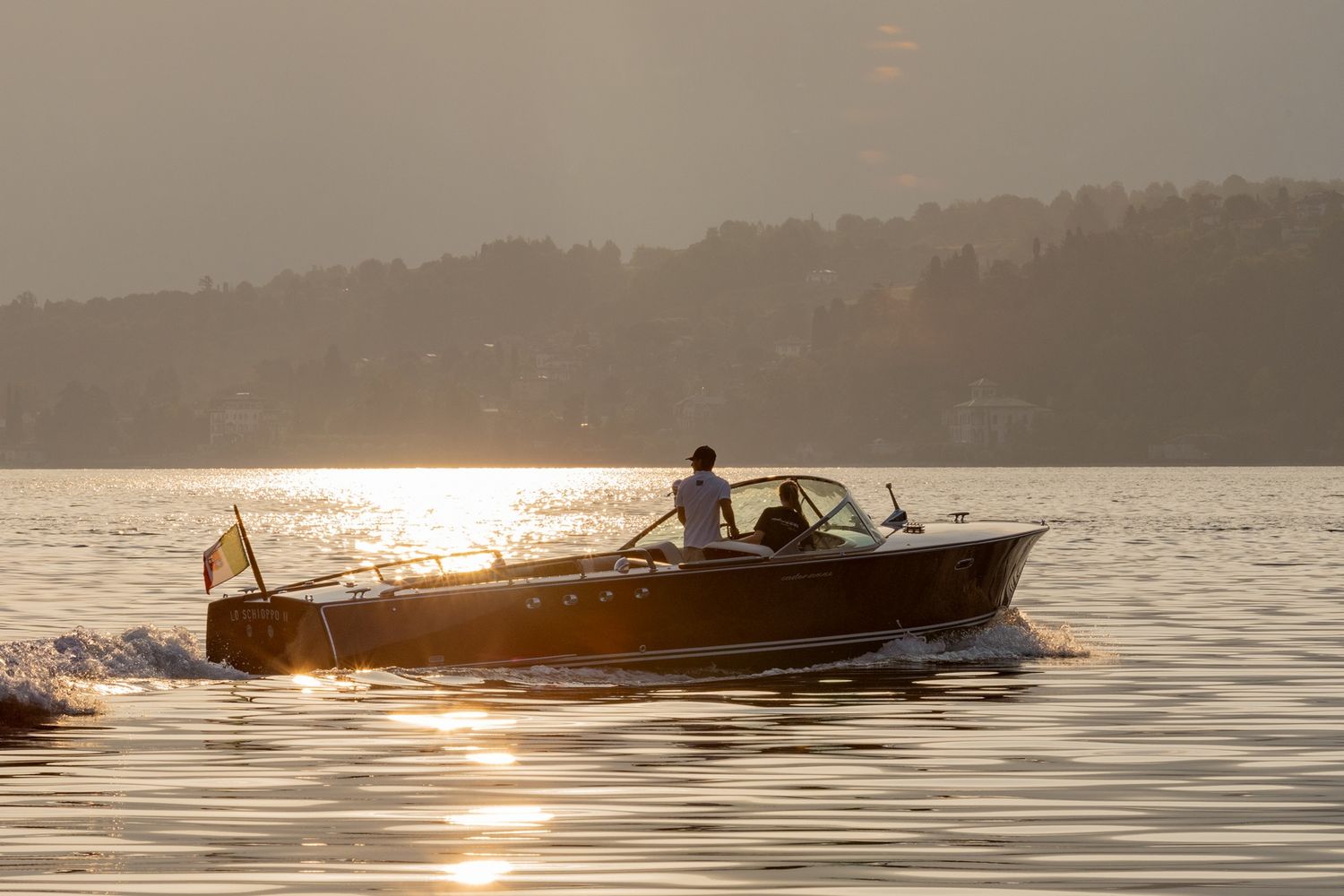 Silhouette of a boat cruising on a lake during golden sunset hour.