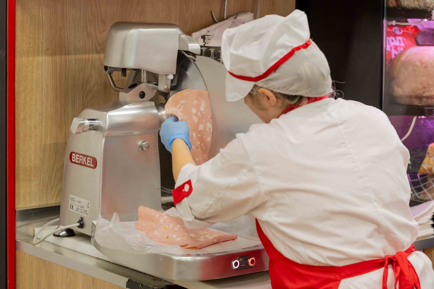Food service workers in white uniforms preparing items at counter.