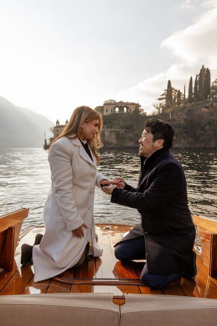 Romantic marriage proposal on a luxury wooden boat with scenic Lake Como villa in background.