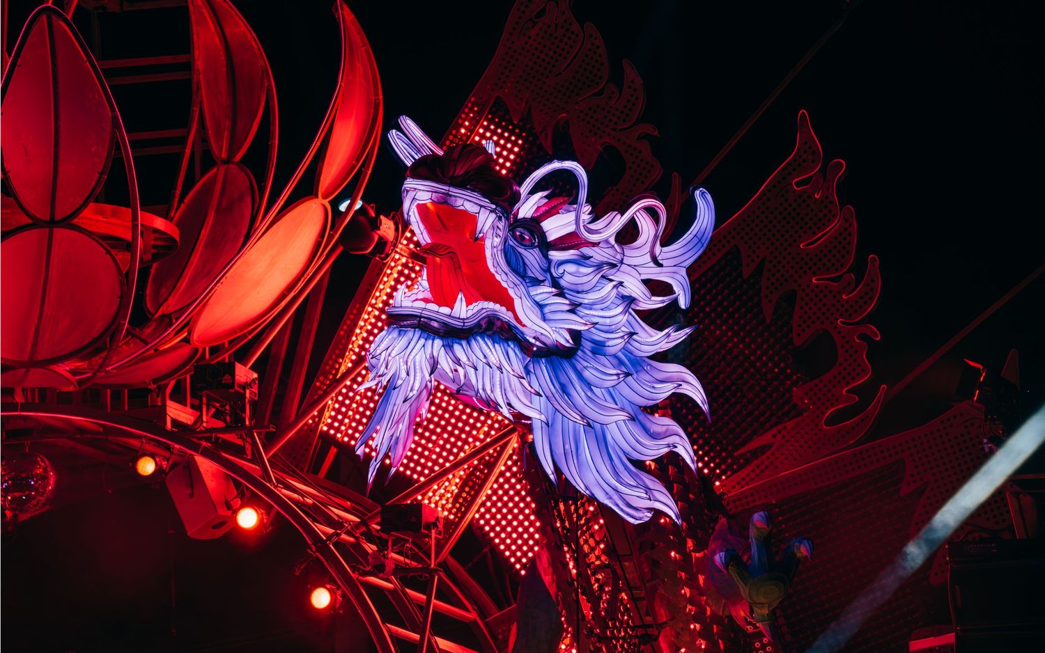 A glowing purple dragon sculpture illuminated by red lights against a dark background.