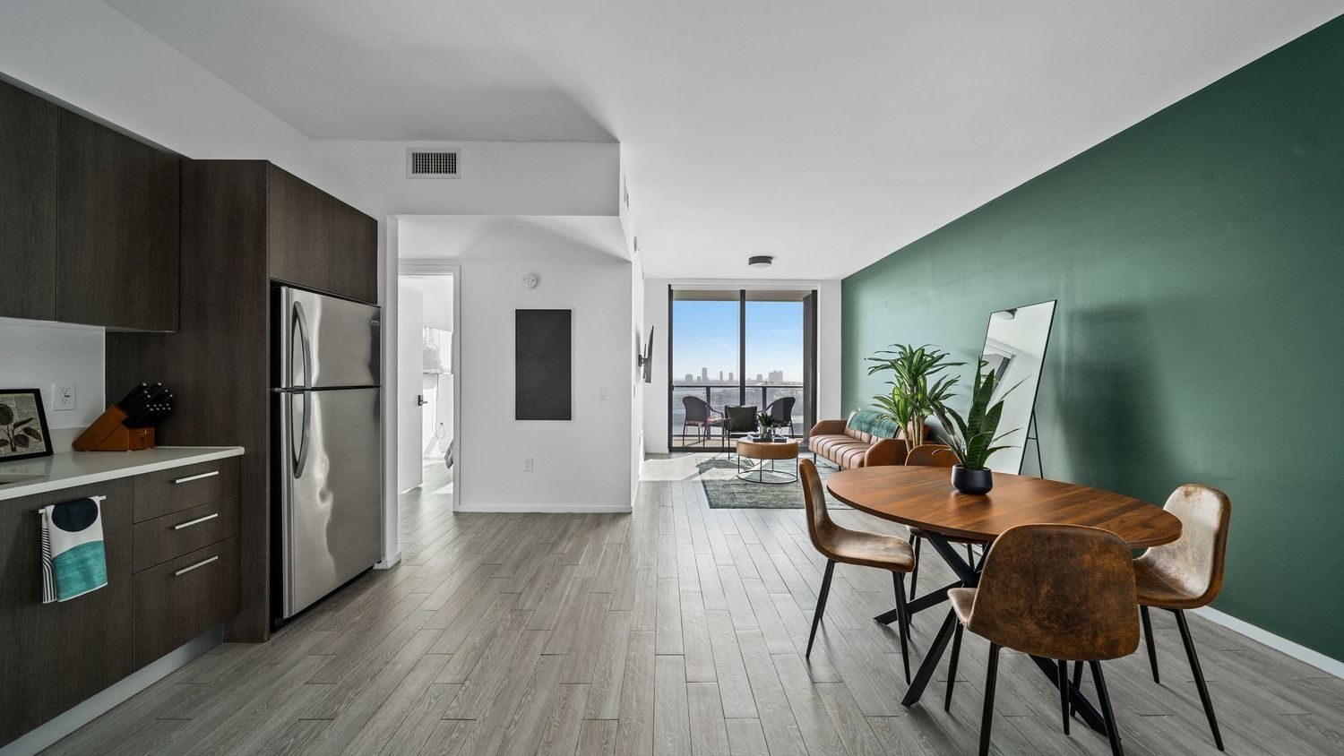 A 360-degree panoramic view of a modern apartment interior with green accent walls and hardwood flooring.