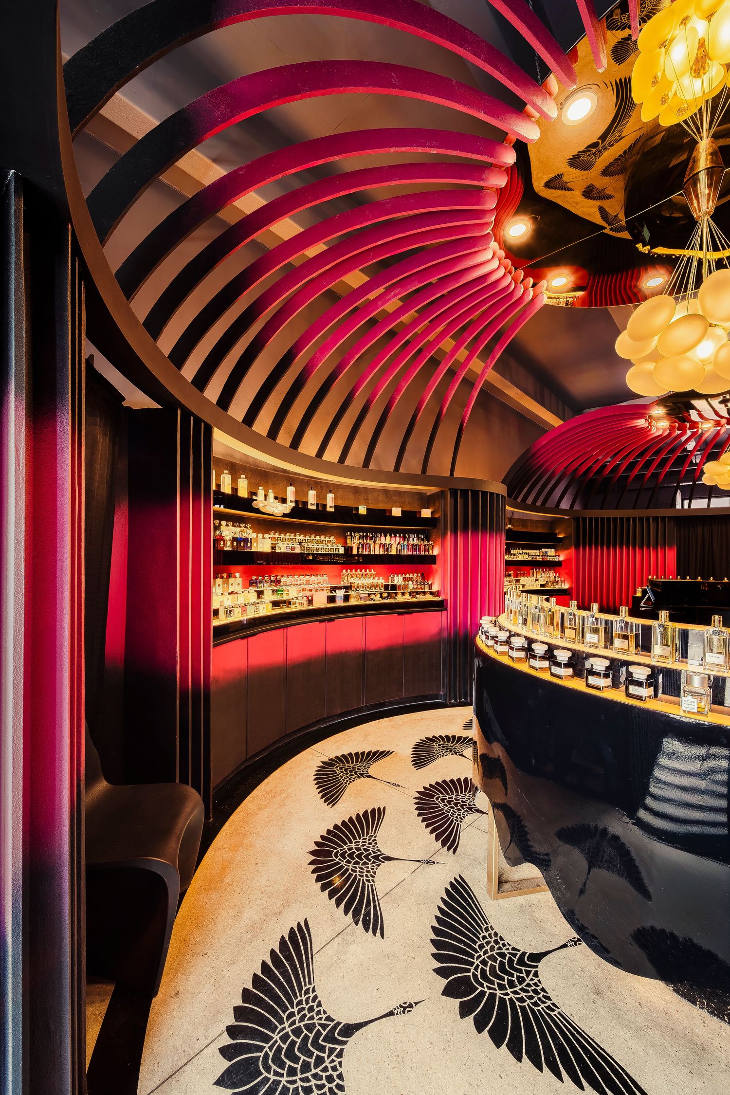 Modern restaurant interior with curved ceiling, red lighting, and black and white bird pattern upholstery on curved seating.