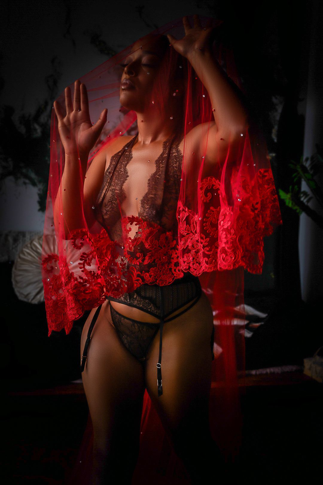 Artistic boudoir photo with red lace robe and lingerie in moody lighting with dramatic shadows.