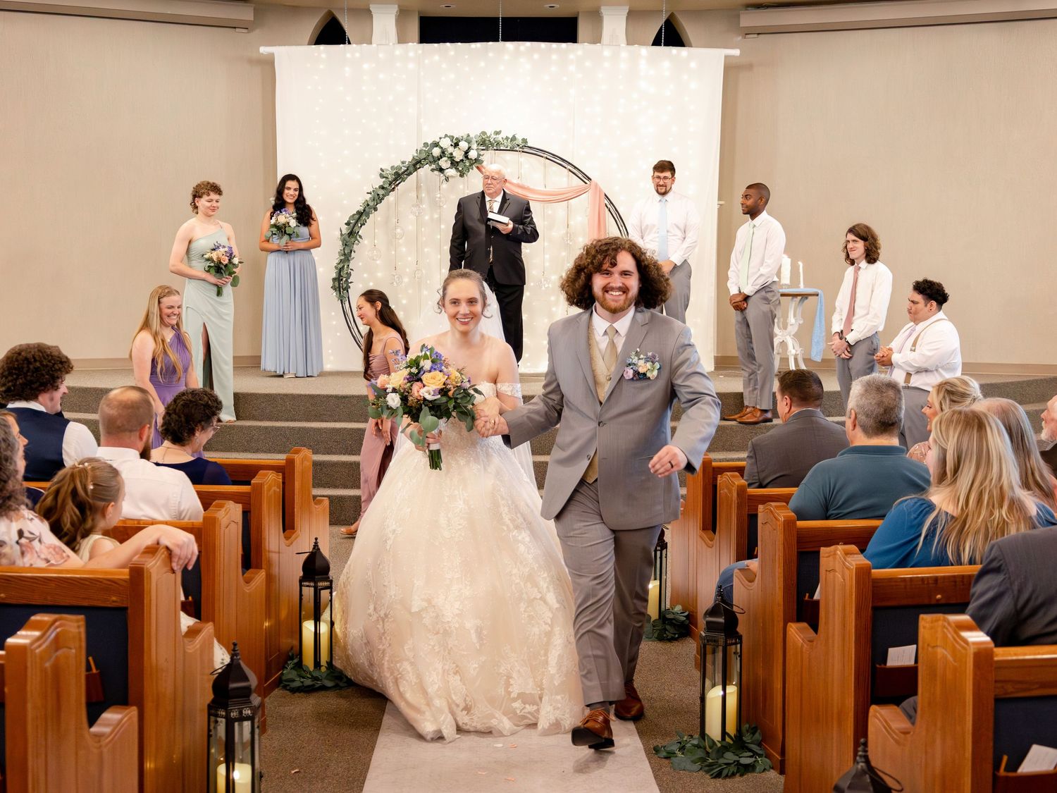 Church wedding ceremony with guests seated in wooden pews watching the celebration.