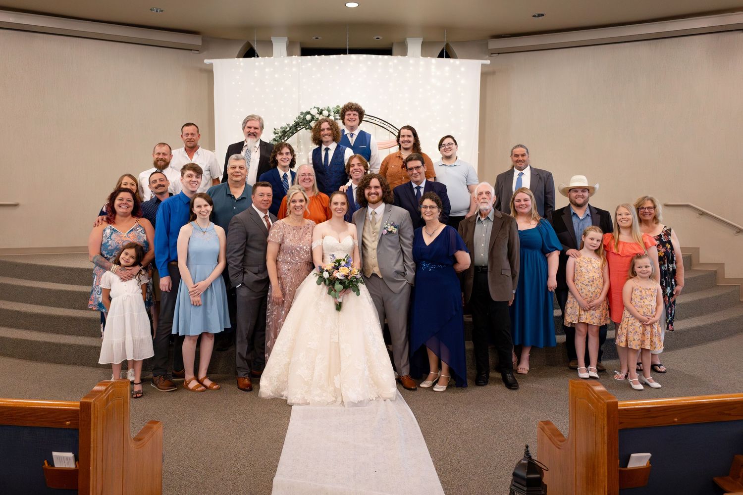 Full wedding party and guests assembled for group photograph in church sanctuary.