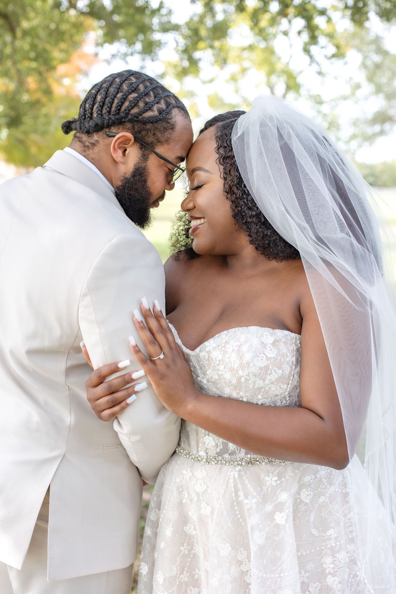 Romantic wedding couple embracing outdoors in white attire.