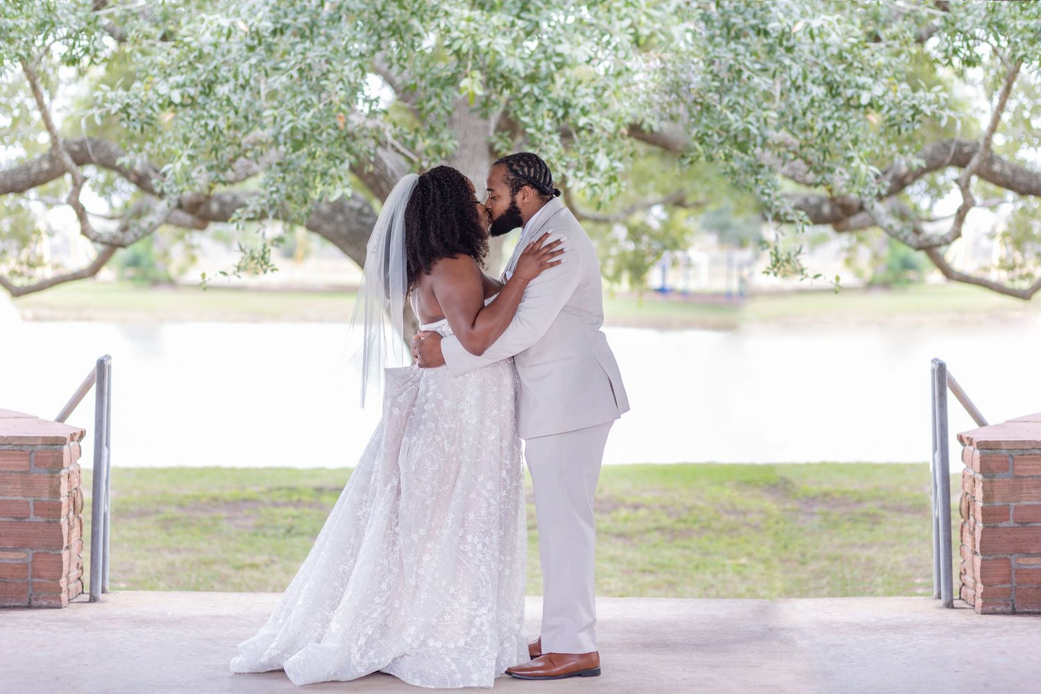A romantic embrace between newlyweds under a gazebo with natural scenery in the background.