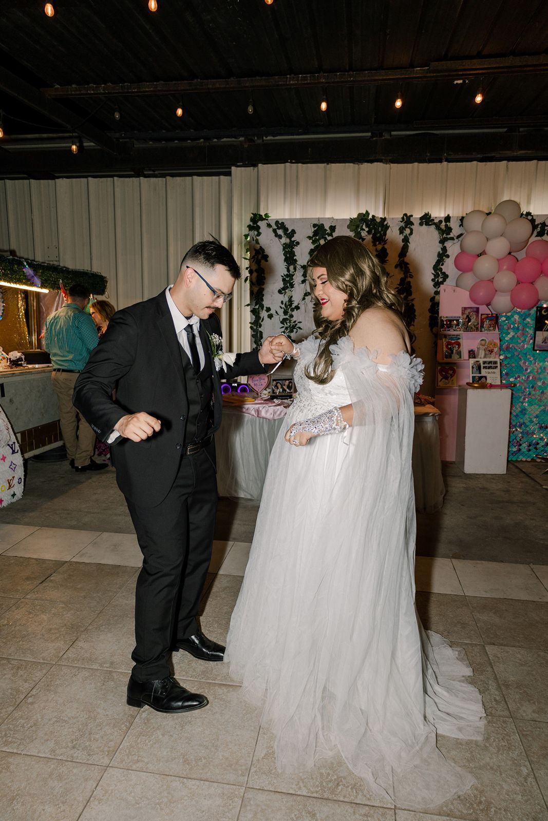 Bride and groom share a joyful moment on the dance floor at their wedding reception with balloon decor.