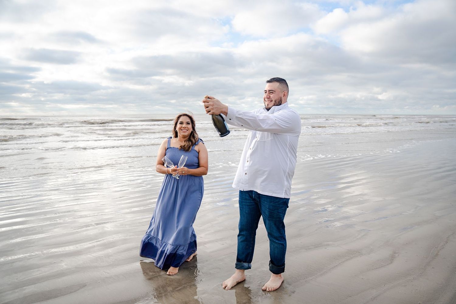 A couple dances together on a misty beach shoreline during a romantic photoshoot session.