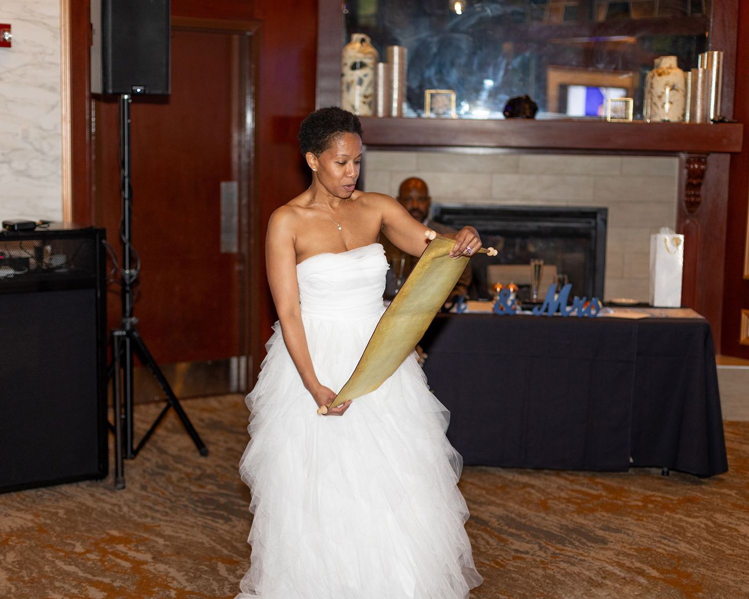 Bride in white strapless ballgown reads a scroll on the dance floor at an elegant wedding reception.
