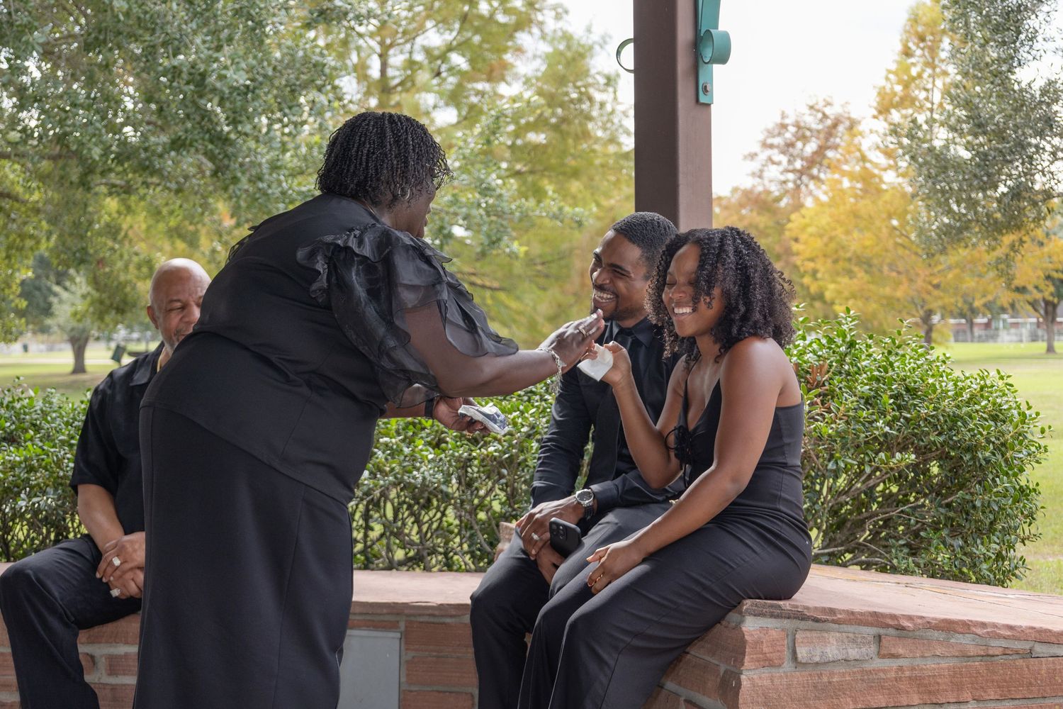 A tender moment between newlyweds captured in black and white under an outdoor pavilion.