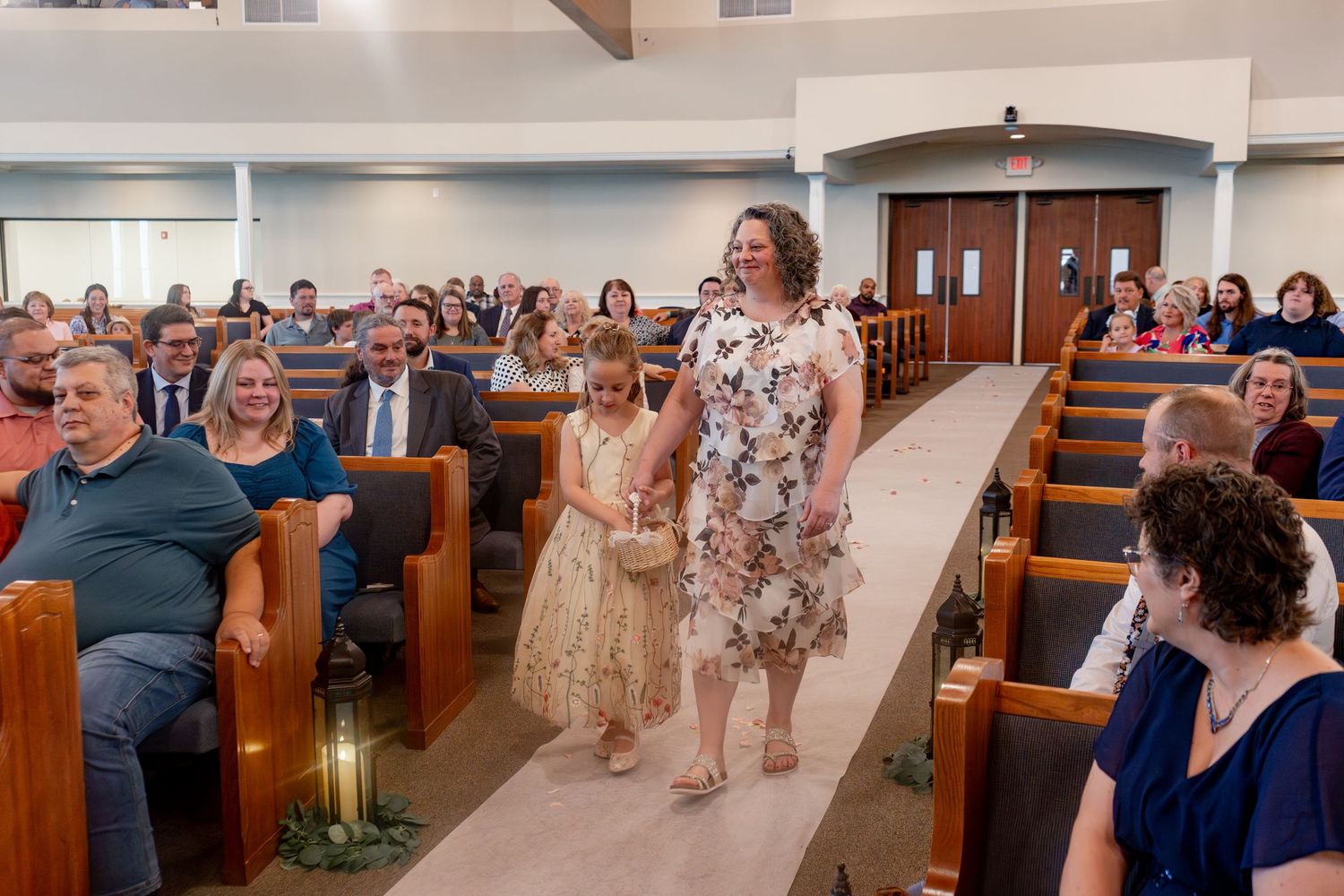 Wedding celebration in a modern church sanctuary with rows of wooden pews filled with guests.