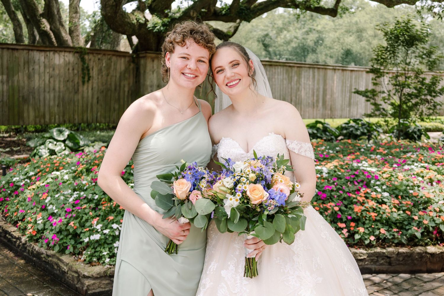 Candid joyful moments captured between wedding party members in an outdoor garden setting.