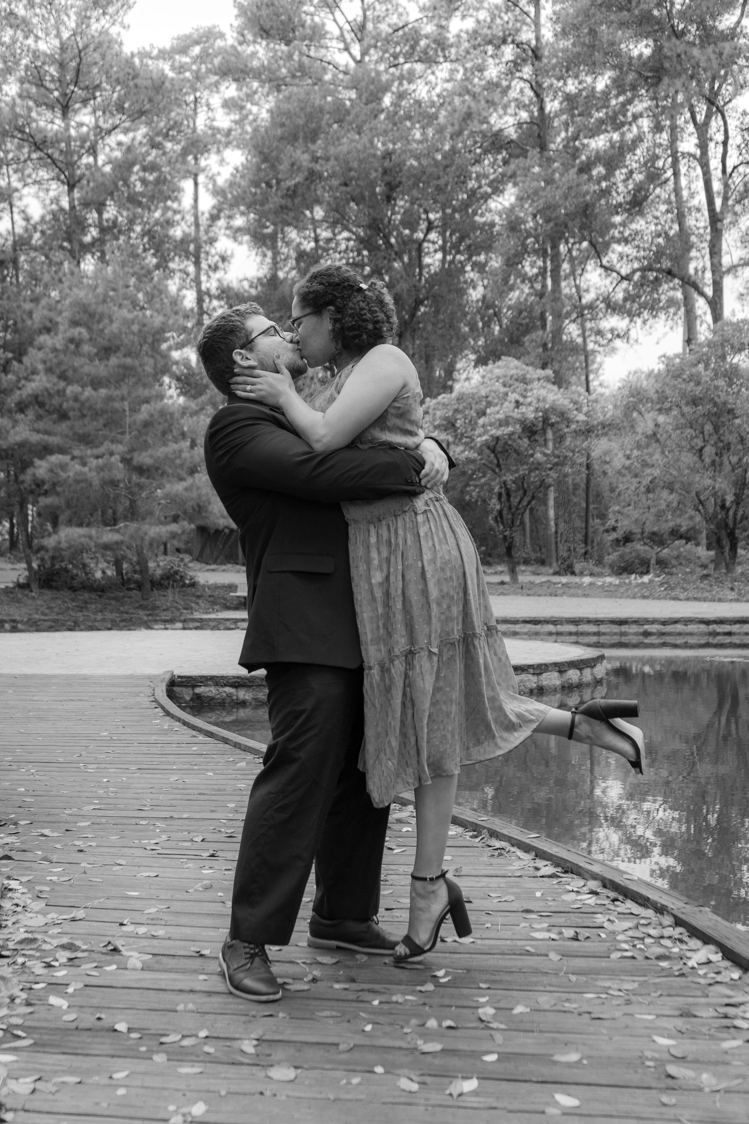 Black and white romantic portraits of a couple on a wooden dock near water.