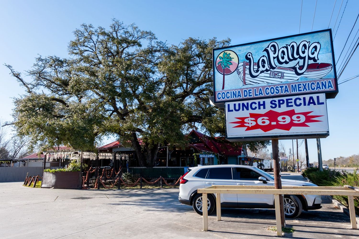 La Panga Mexican restaurant sign advertising a $6.99 lunch special with outdoor seating and large oak tree.