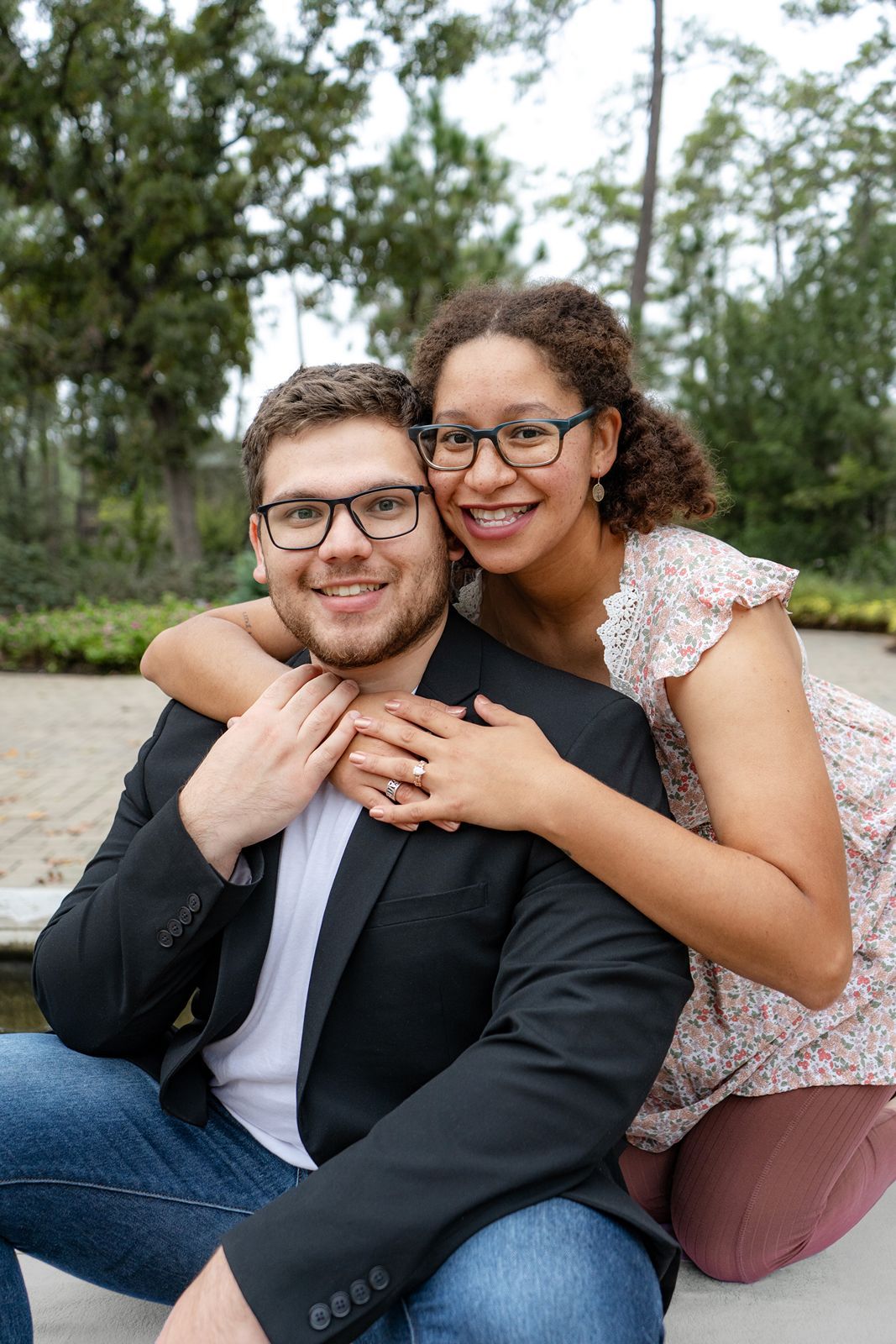A couple in casual and formal attire share intimate moments while sitting together outdoors.