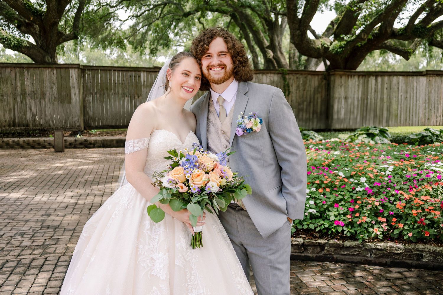 Romantic garden wedding photos with couple in white gown and gray suit.