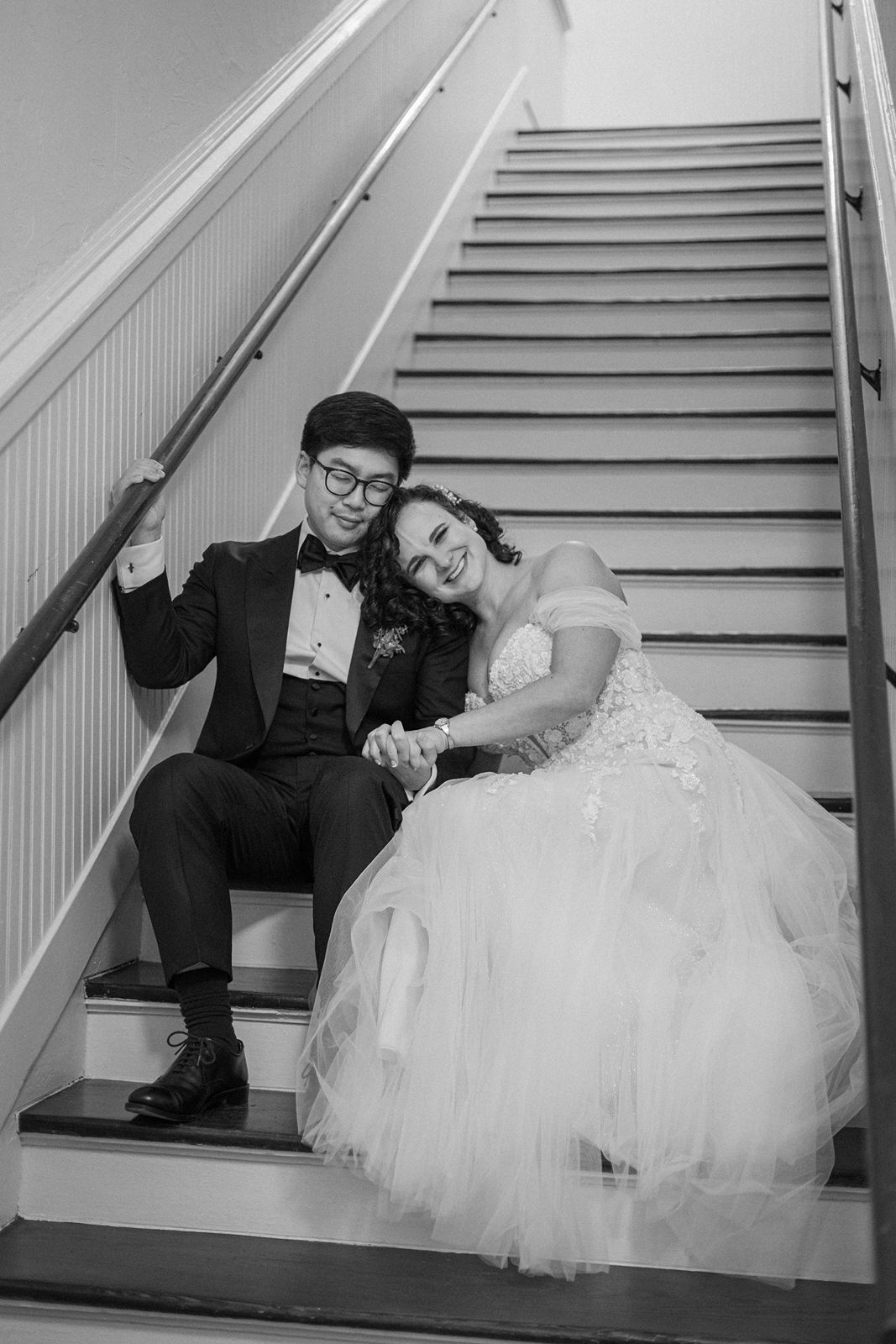 A bride and groom pose playfully on white stairs in a series of black and white wedding photos.