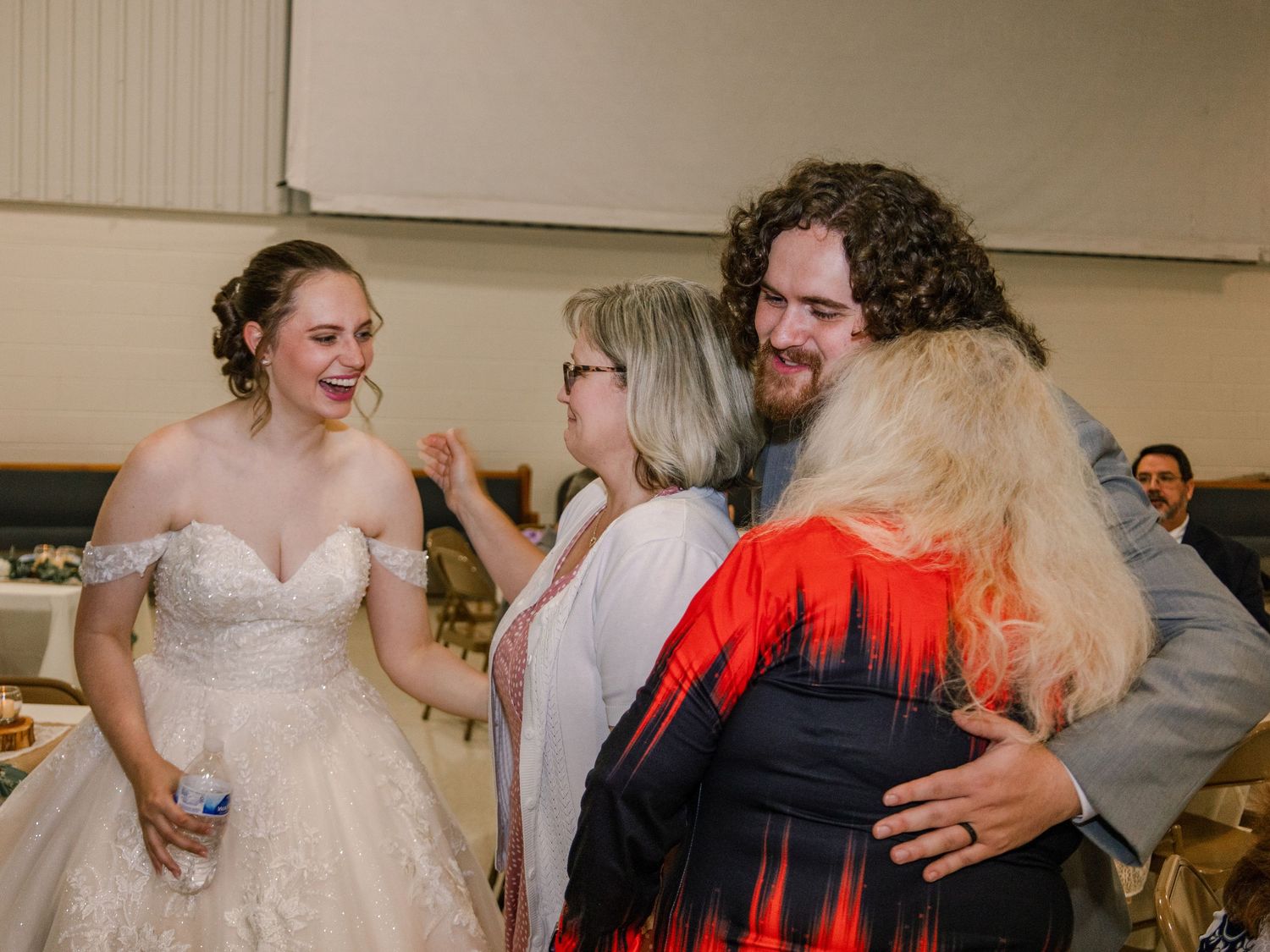 Wedding celebration moment with guests sharing embraces at a reception.