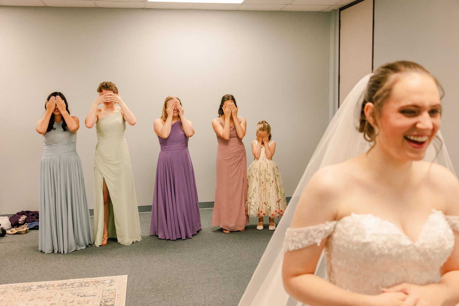 Bridesmaids in pastel dresses gather during wedding day preparations.