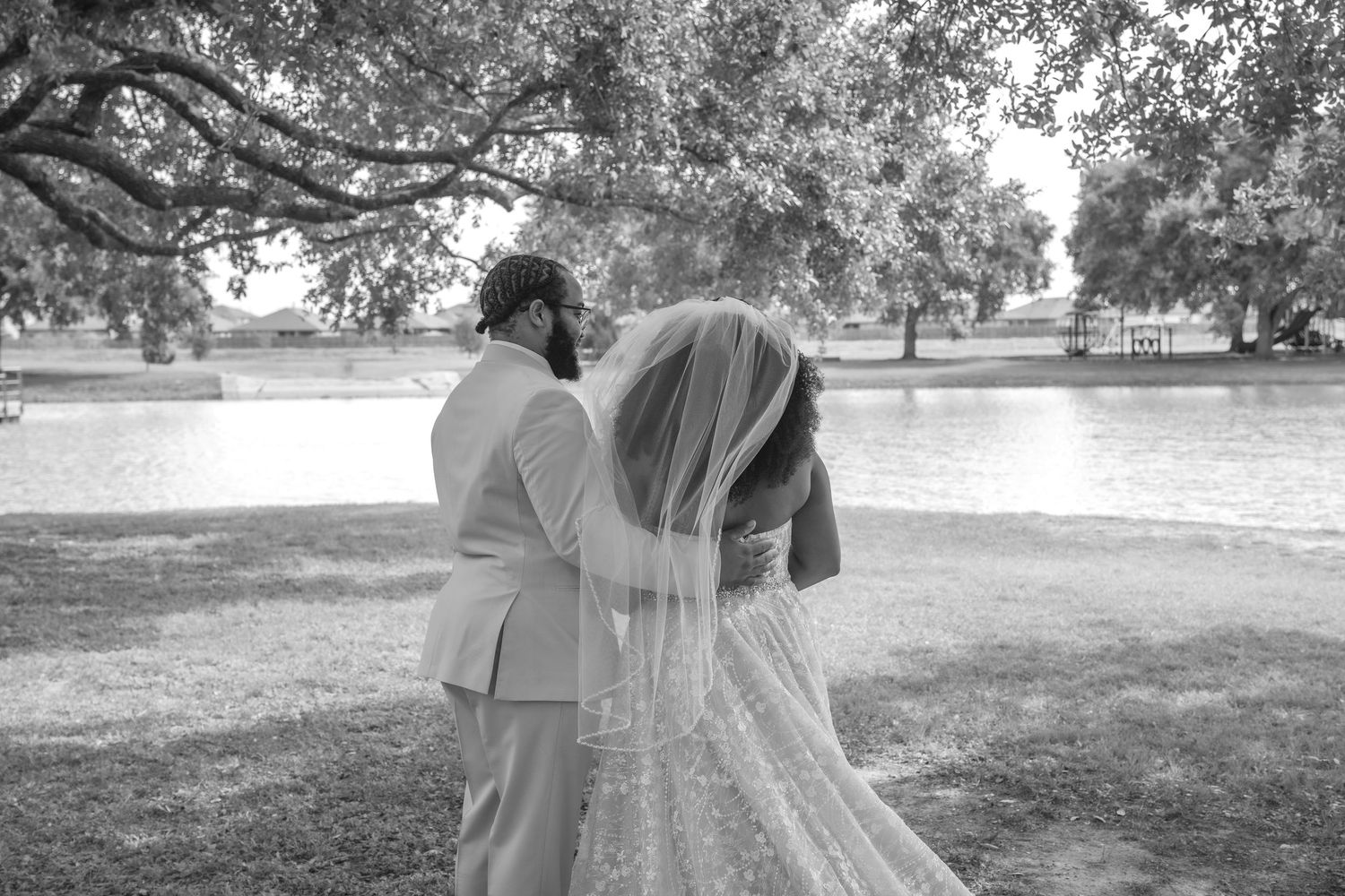 A black and white romantic wedding portrait captured near a serene lake.