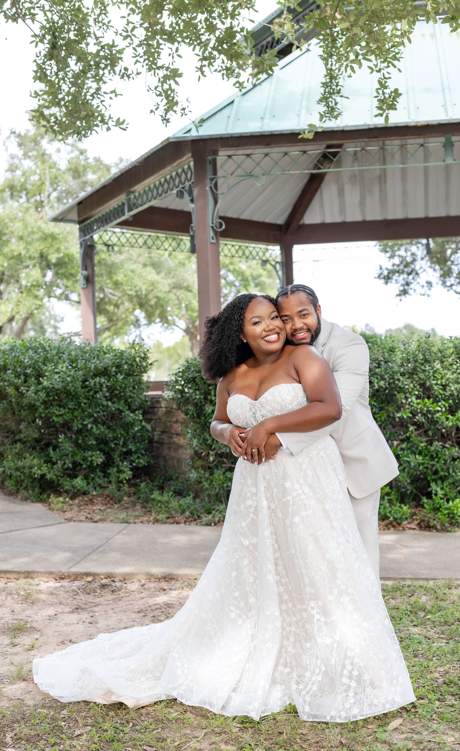 Happy couple embraces and laughs during outdoor wedding photoshoot.