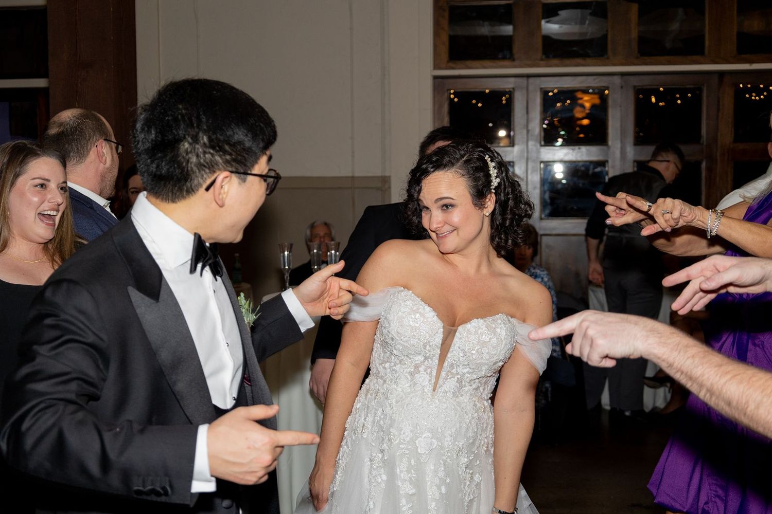 Couples dancing together at a wedding reception in a dimly lit ballroom with festive decorations.
