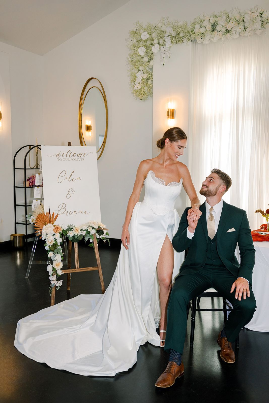 A romantic fall wedding showing a newlywed couple in white dress and dark suit smiling at each other at their reception.