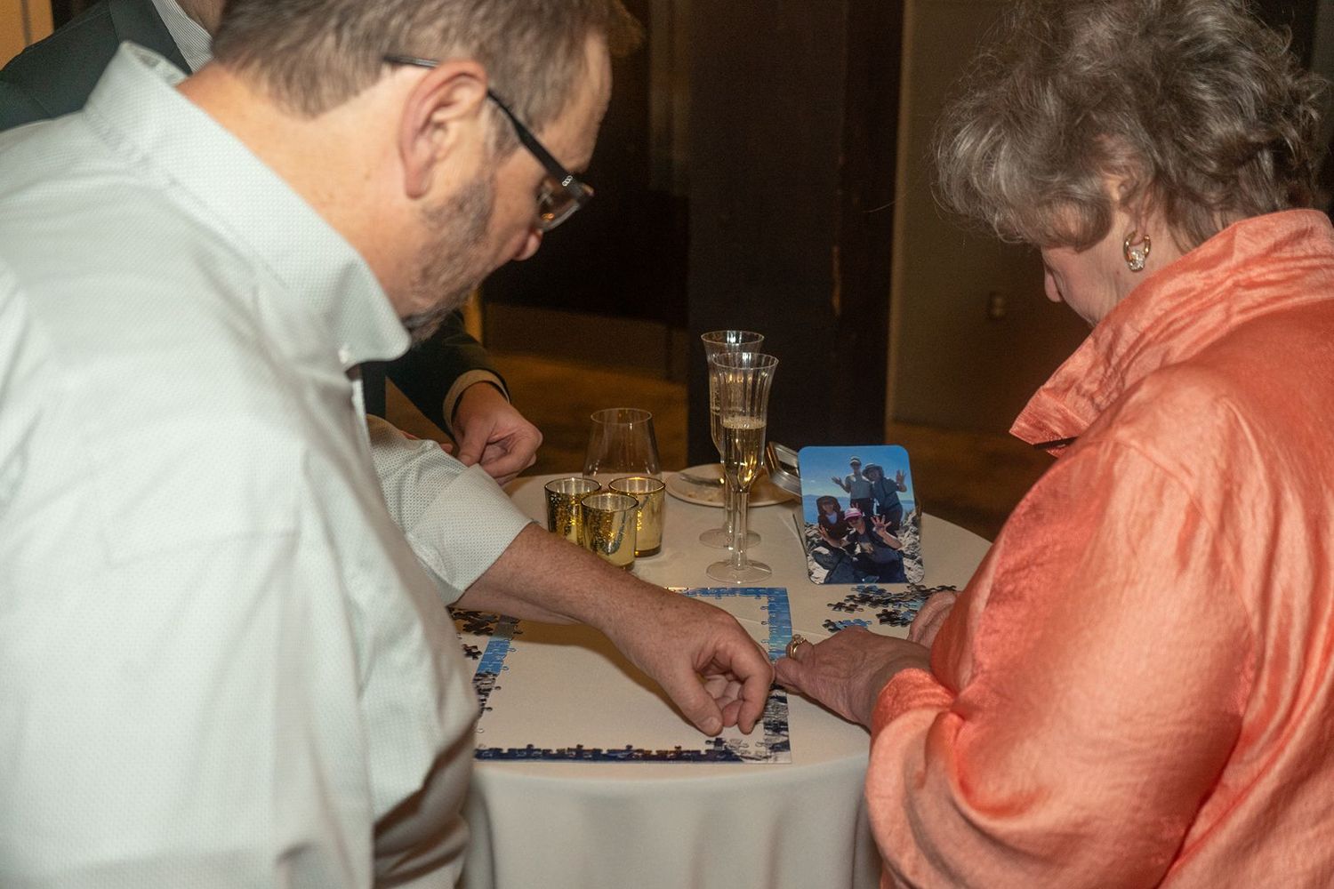 People sitting at a table playing a board game together in a casual indoor setting.