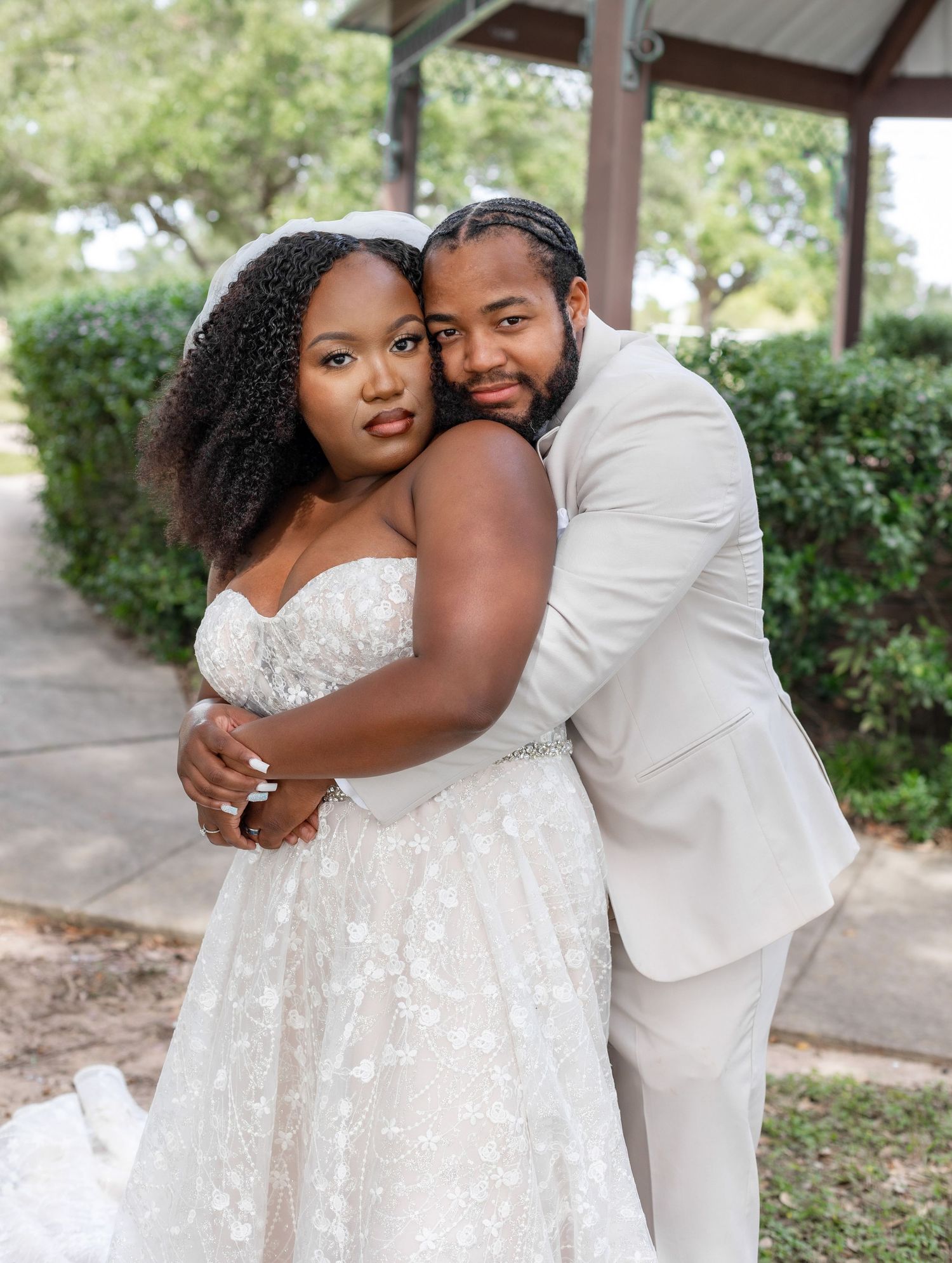 Wedding portraits show tender moments between couple in white attire under covered pavilion.