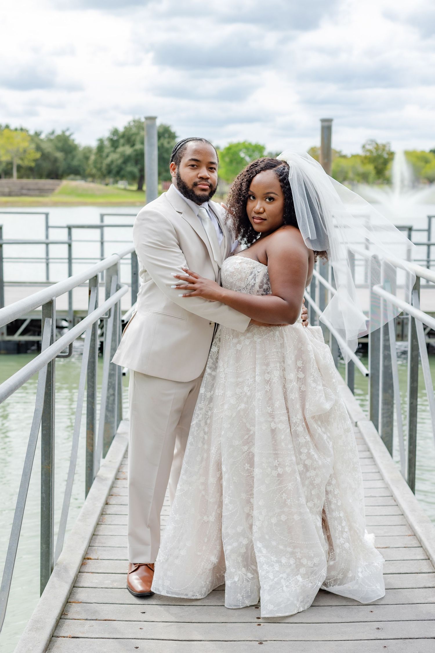Romantic wedding photoshoot on lakeside dock with couple in matching white outfits.