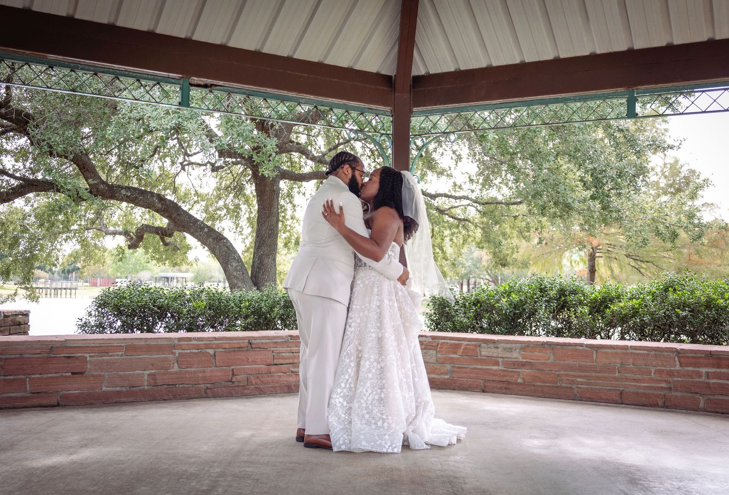 A romantic scene under a gazebo with trees and greenery in the background.