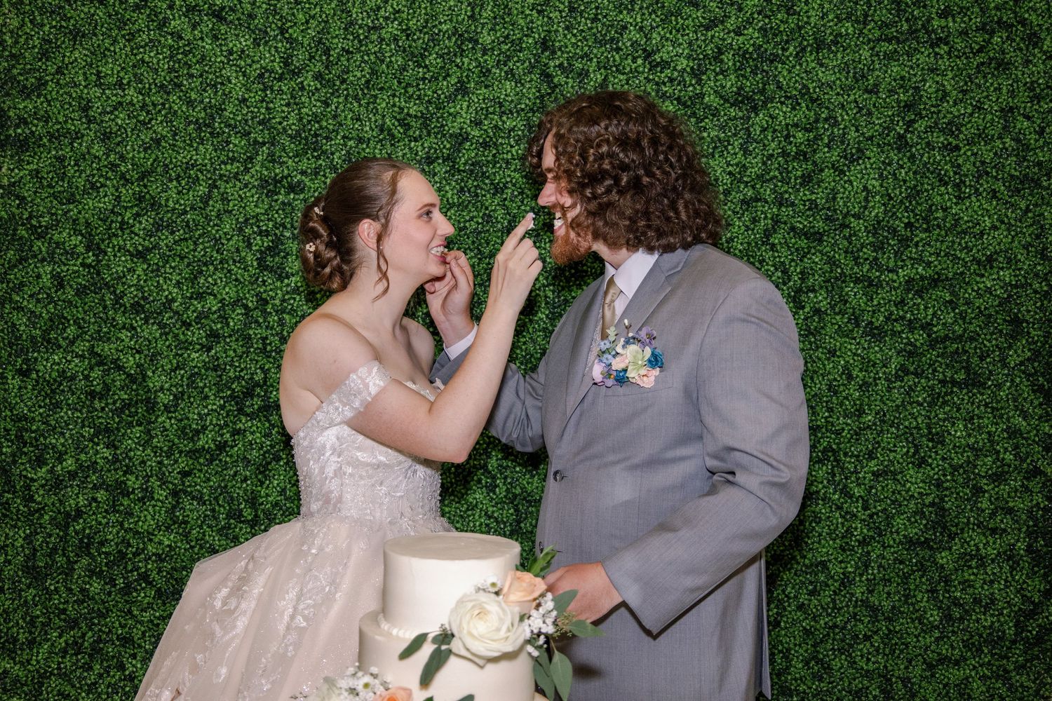 Wedding couple playfully feeds each other cake during their reception celebration.