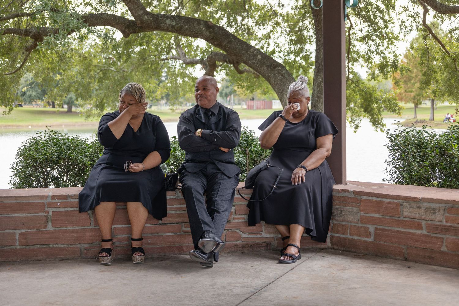 Wedding guests in casual attire relax on a brick ledge under a covered patio.