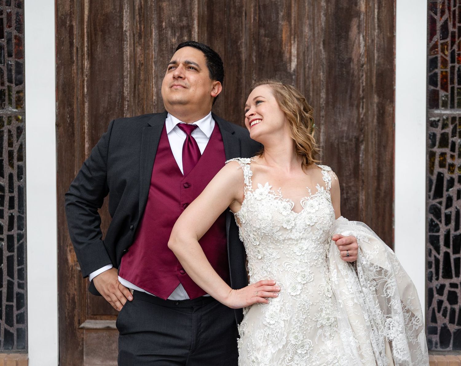 Bride and groom share a romantic moment laughing together before rustic wooden doors.
