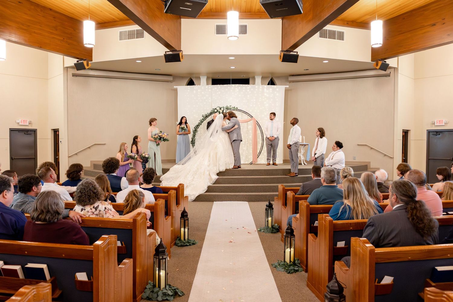 Wedding ceremony in a church sanctuary with wooden pews and exposed beam ceiling.