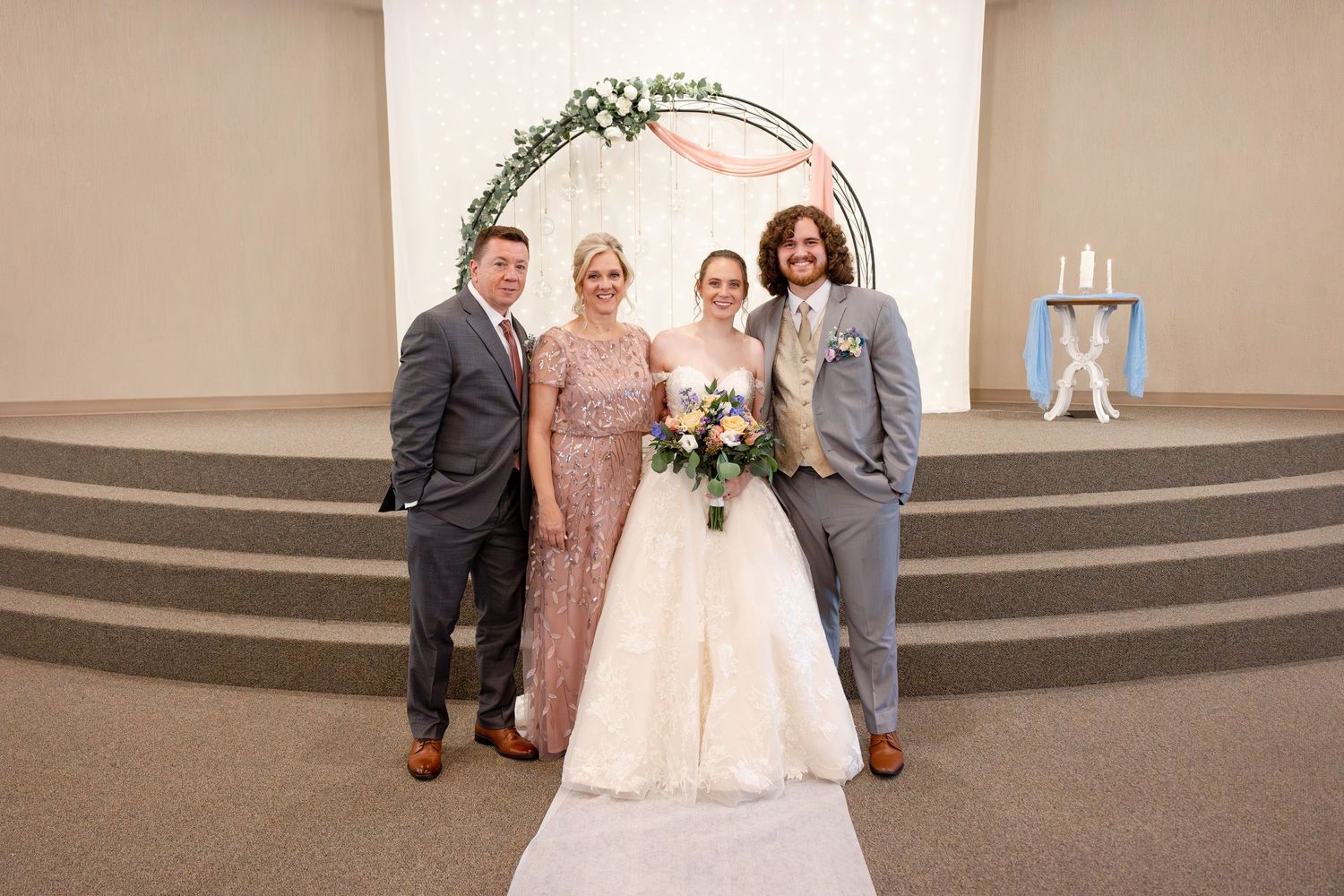 Wedding party gathered for formal photographs in front of church altar.