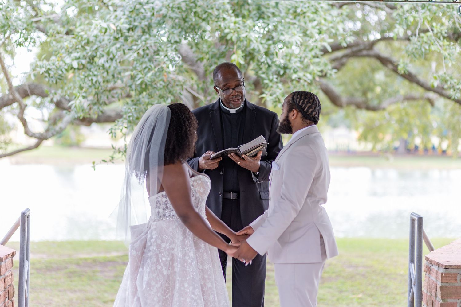Wedding ceremony taking place in an outdoor pavilion overlooking a lake.