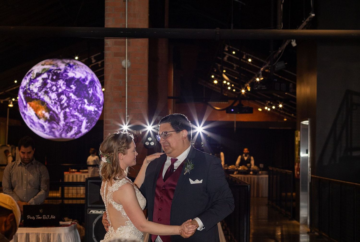 Couple shares first dance under a glowing purple globe light at their wedding reception.