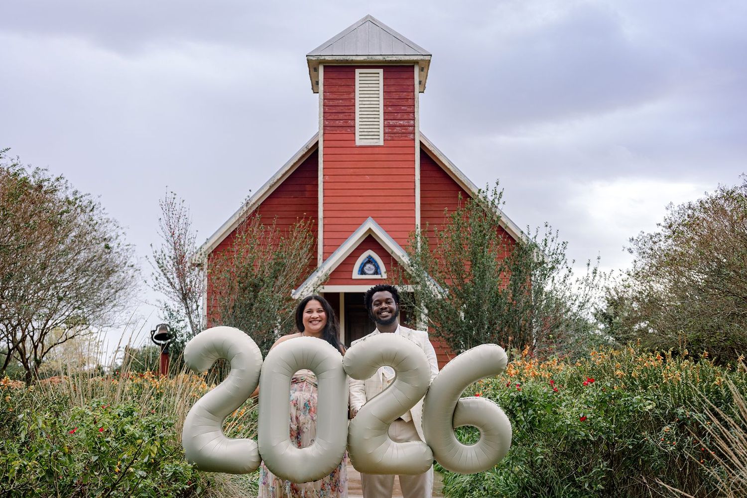 A red barn building with white inflatable Christmas decorations displayed in front during the holiday season.