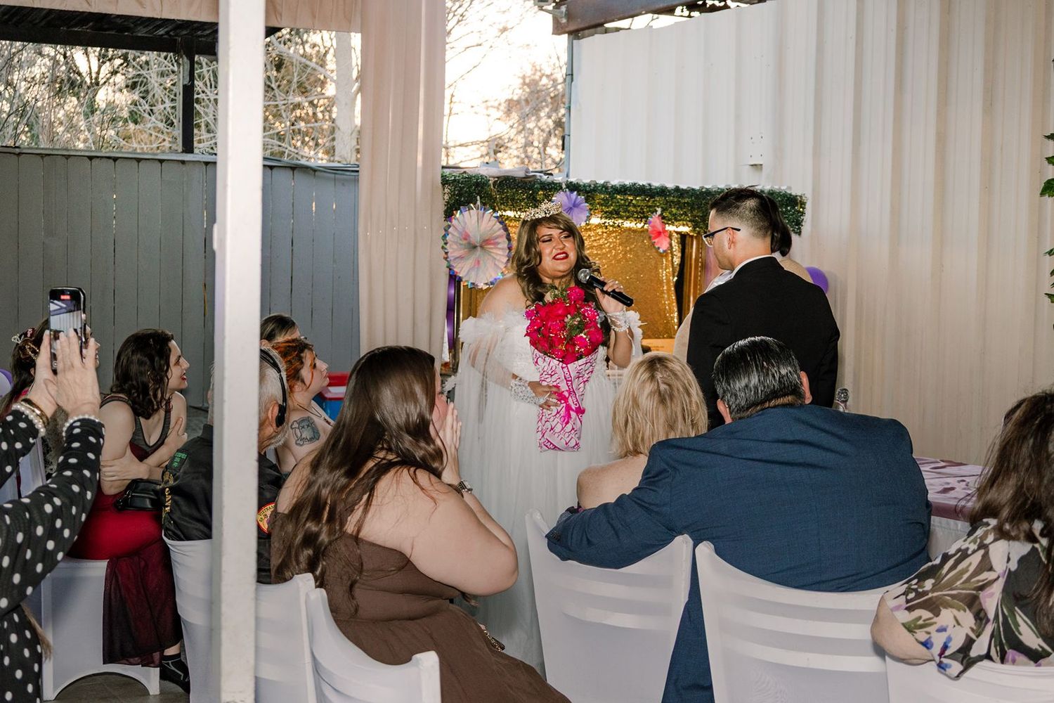 Bride walks down aisle at intimate outdoor wedding ceremony with seated guests.
