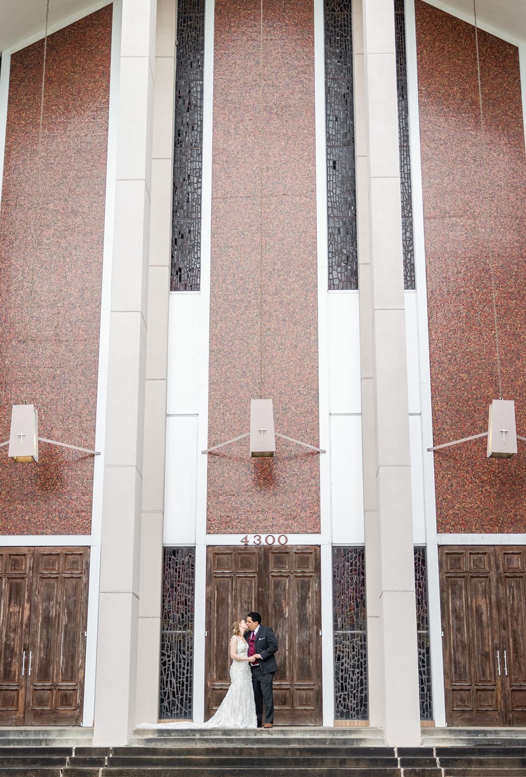 Modern church interior with tall white columns and wooden paneling along walls, featuring vertical lighting elements.